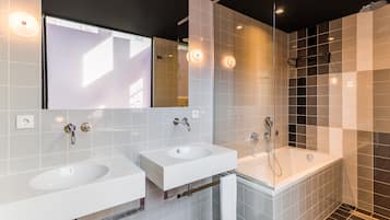 A modern bathroom with two sinks, a bathtub, and a glass shower enclosure.