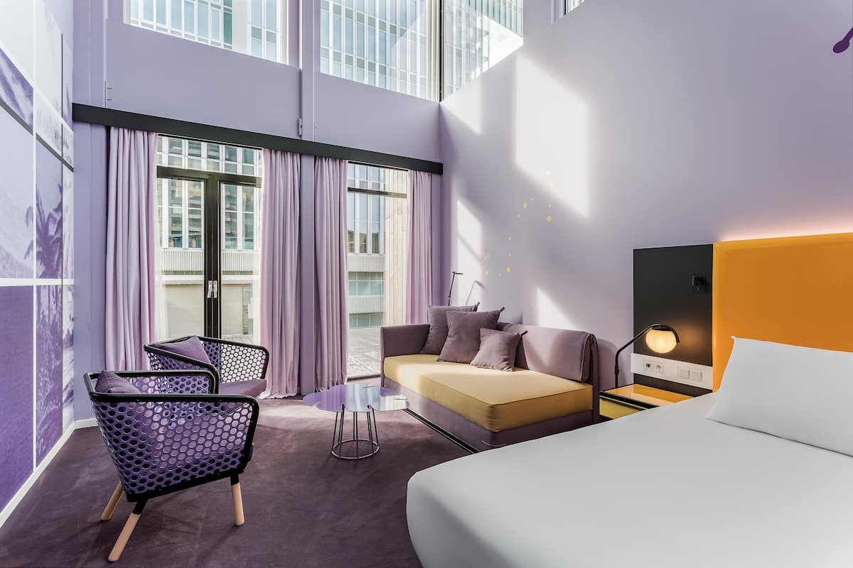 Une chambre d’hôtel moderne équipée d’un canapé, d’un lit, d’un bureau et d’une chaise.