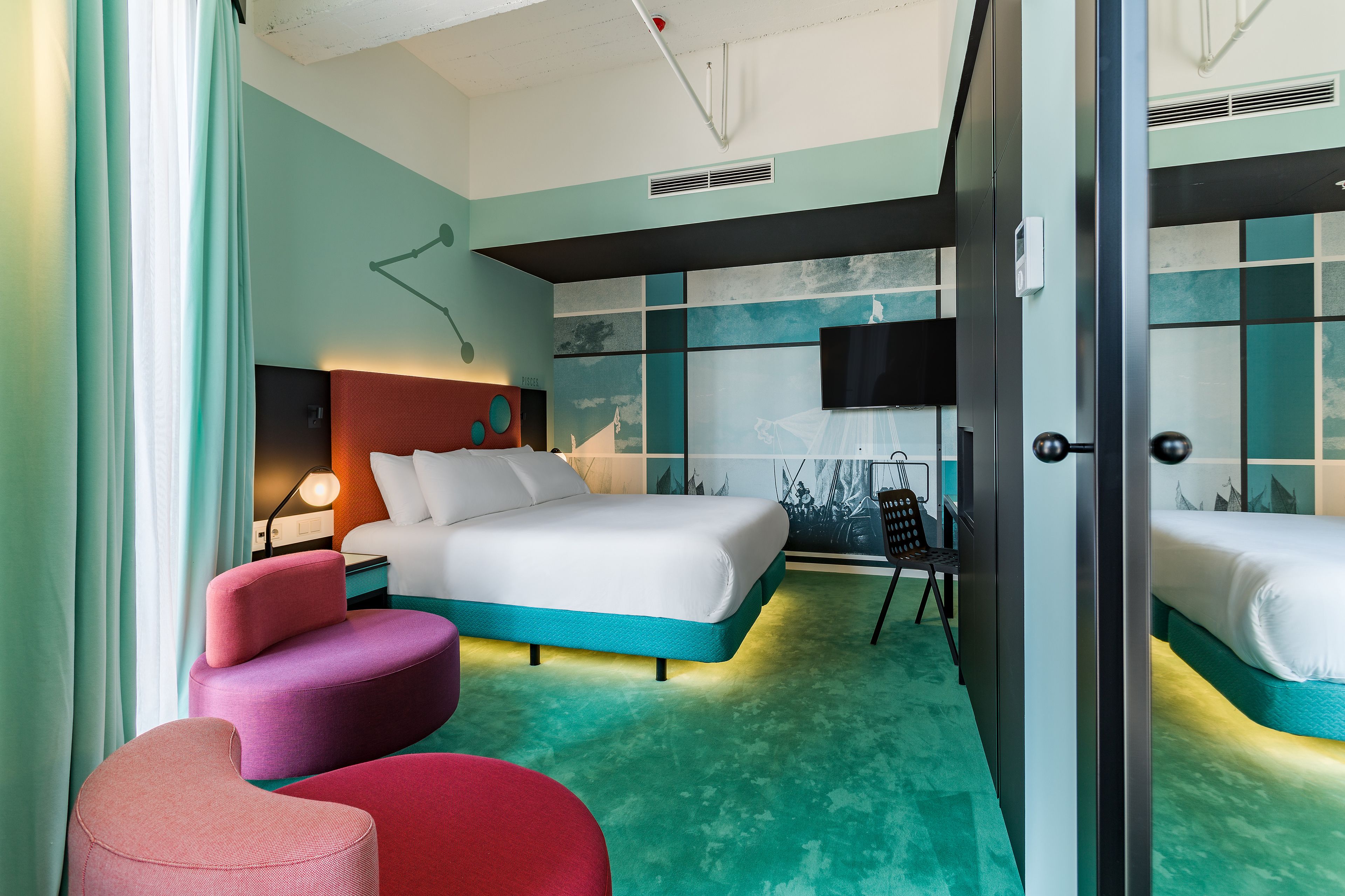 A hotel room with a bed, a desk, a chair, and a TV.