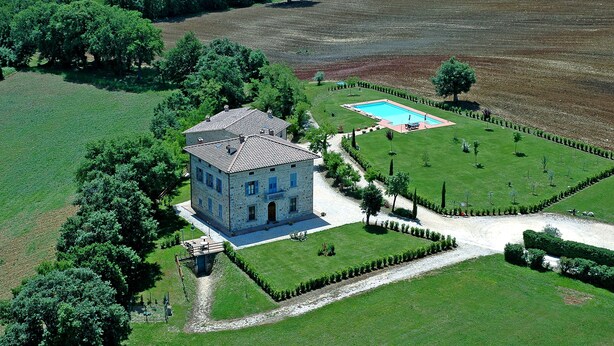 An aerial view of a stone house with a swimming pool, surrounded by well-maintained lawns and trees. - Bazzani Apartments (Casole d'Elsa)