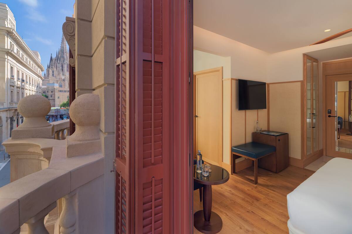 Ein Hotelzimmer mit Balkon, Fernseher, kleinem Tisch und Bett.