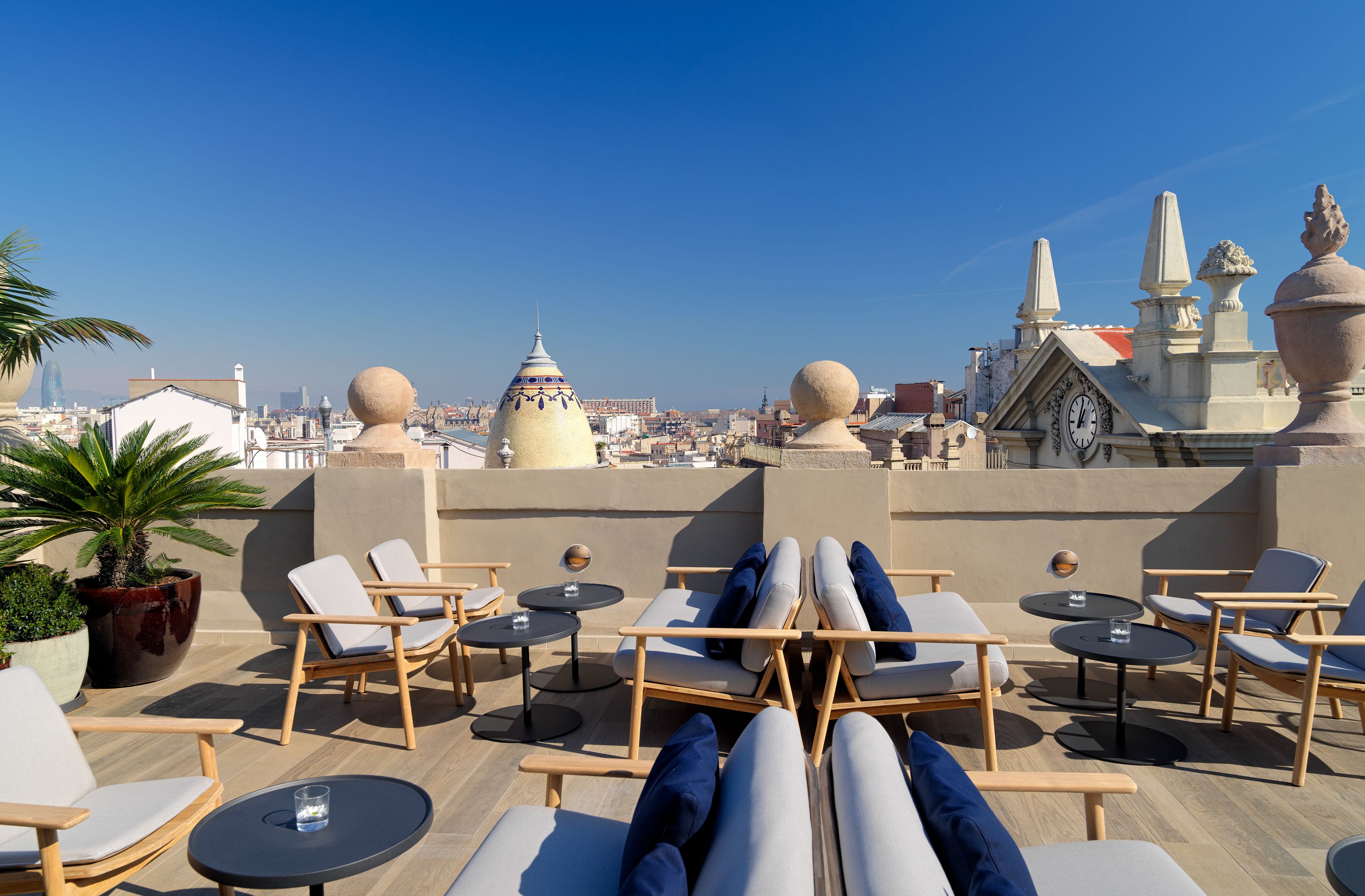 Terraza en la azotea con sillones y mesas, con vistas a la ciudad.
