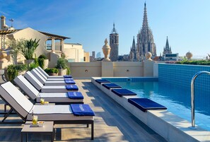 Piscina no terraço com espreguiçadeiras e vista para uma catedral.
