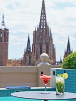 A table with two drinks and a view of a cathedral in the background.