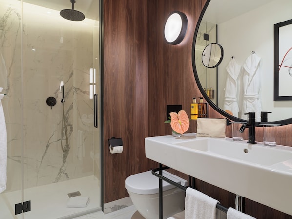 A modern bathroom with a glass-enclosed shower, a white sink with a black faucet, and a large mirror.