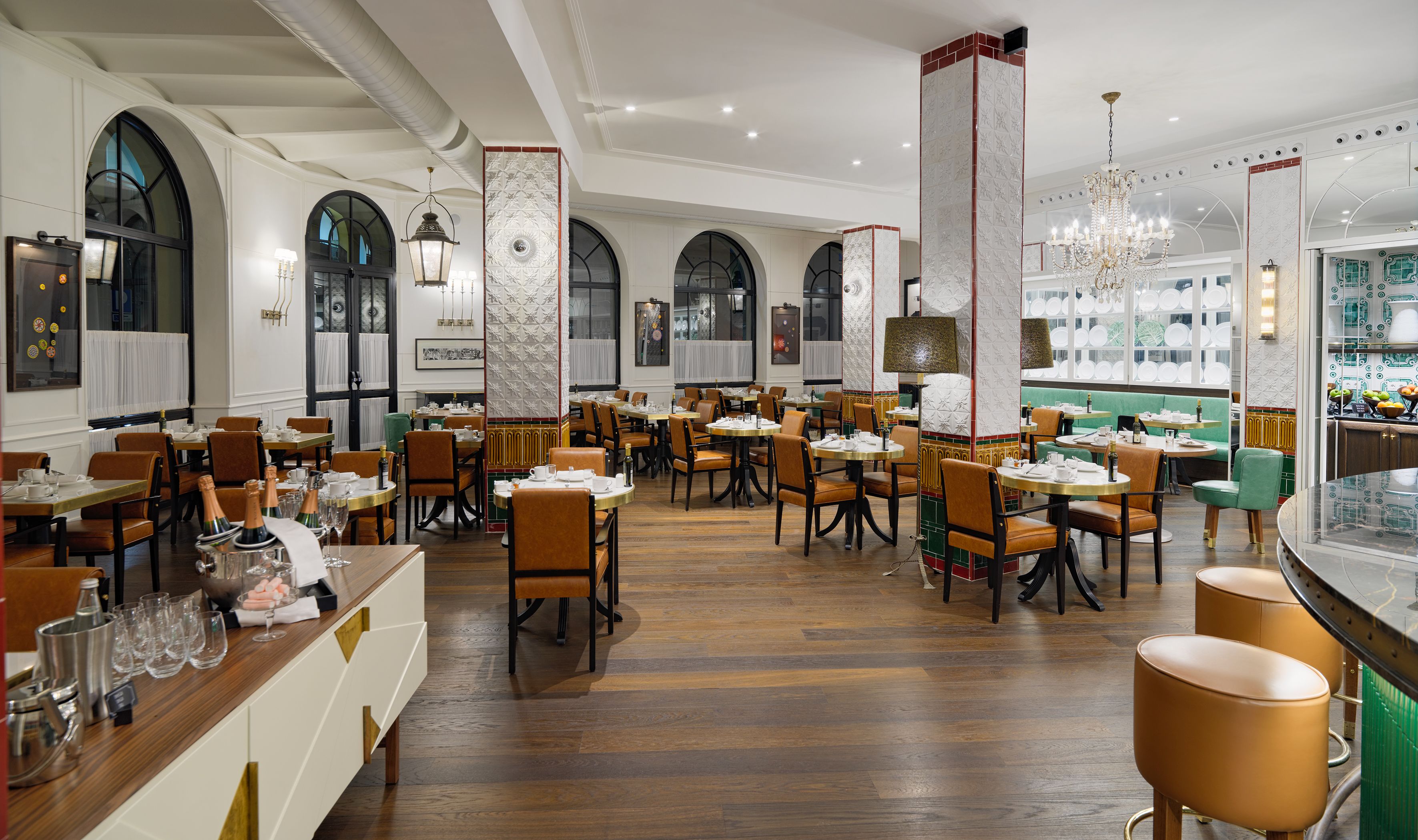 A spacious restaurant with high ceilings, arched windows, and a variety of seating arrangements including tables and booths.