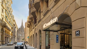 A hotel with a modern entrance, a clear sign indicating it is a 4-star hotel, and a view of the surrounding historic architecture. - H10 Madison (Barcelona)