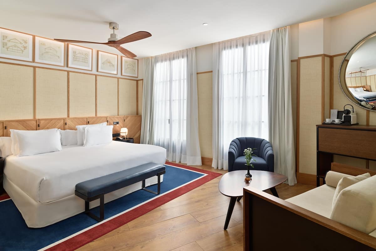 Ein Hotelzimmer mit einem großen Bett, einem Schreibtisch, einem Stuhl und einem Deckenventilator.