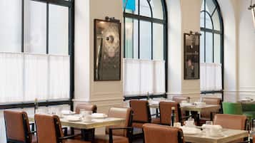 A restaurant with high arched windows, leather chairs, and tables set for dining.