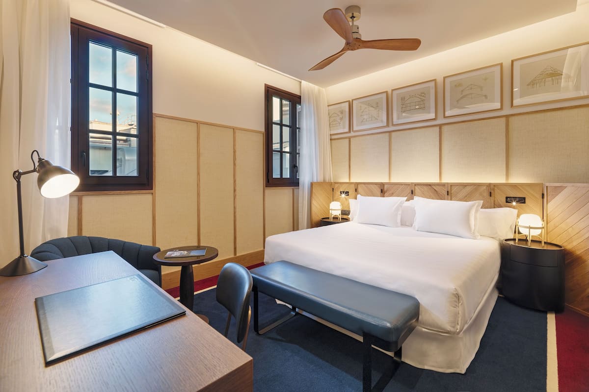 Ein Hotelzimmer mit Bett, Schreibtisch, Stuhl und Deckenventilator.