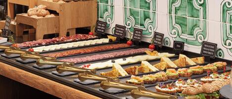 A buffet with various food options including bread, meats, cheeses, and salads.