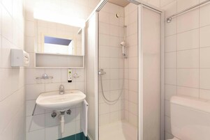 Un baño moderno con lavamanos blanco, cabina de ducha de vidrio y un inodoro.