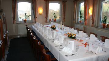 A long dining table set for a formal event with white tablecloths, candles, and floral centerpieces.