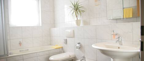 A bathroom with a toilet, bidet, sink, and a potted plant.