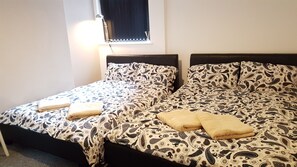 Un lit double avec une parure de lit à motifs et deux oreillers, une table de chevet et une fenêtre avec des rideaux.