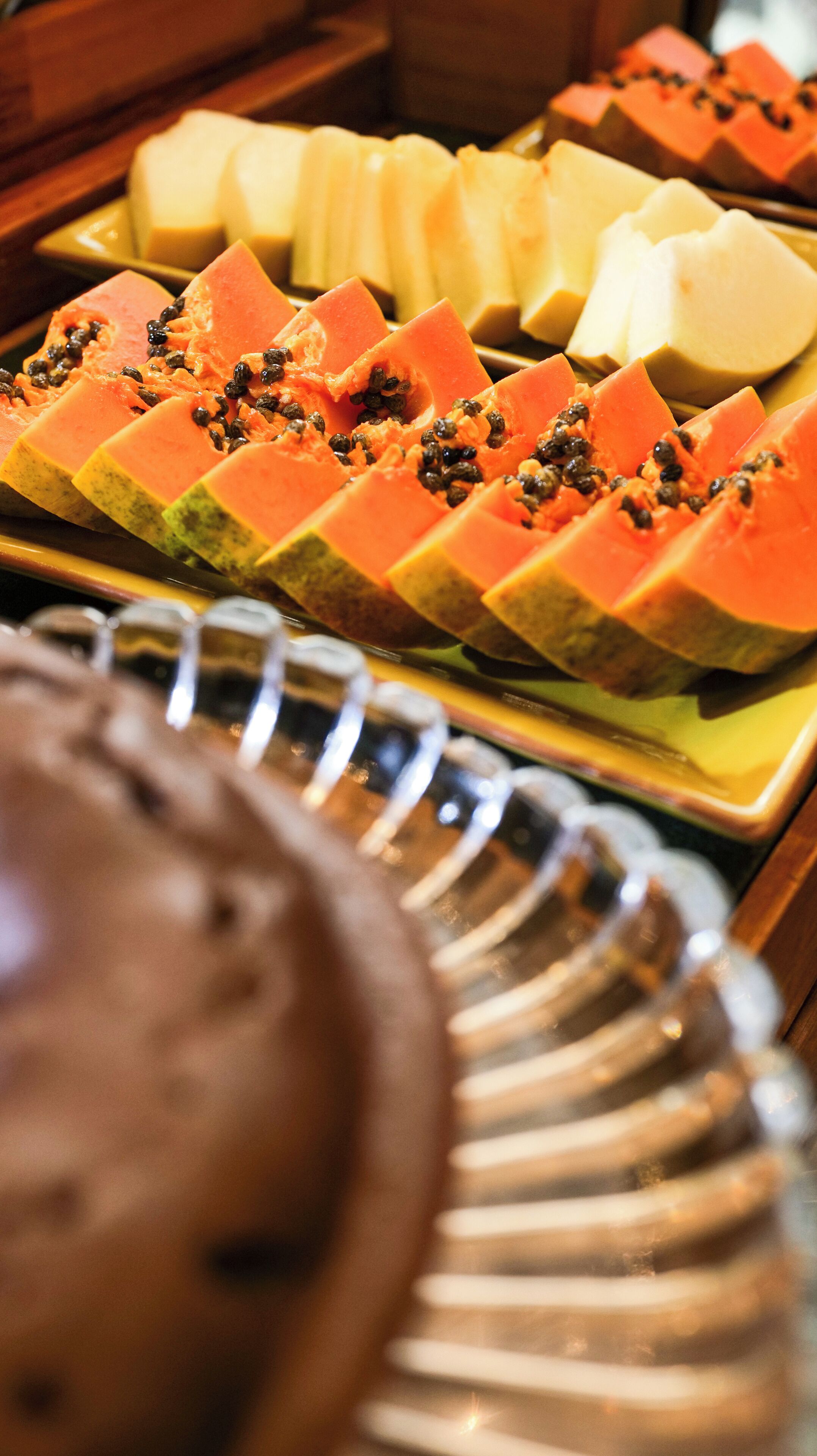 Un bufé con diversos alimentos, incluyendo frutas cortadas y una fuente de pan.