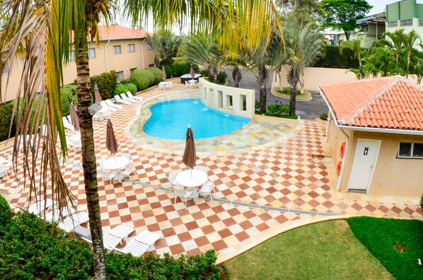 Un espace piscine doté d’un sol à carreaux, de chaises longues et de parasols.