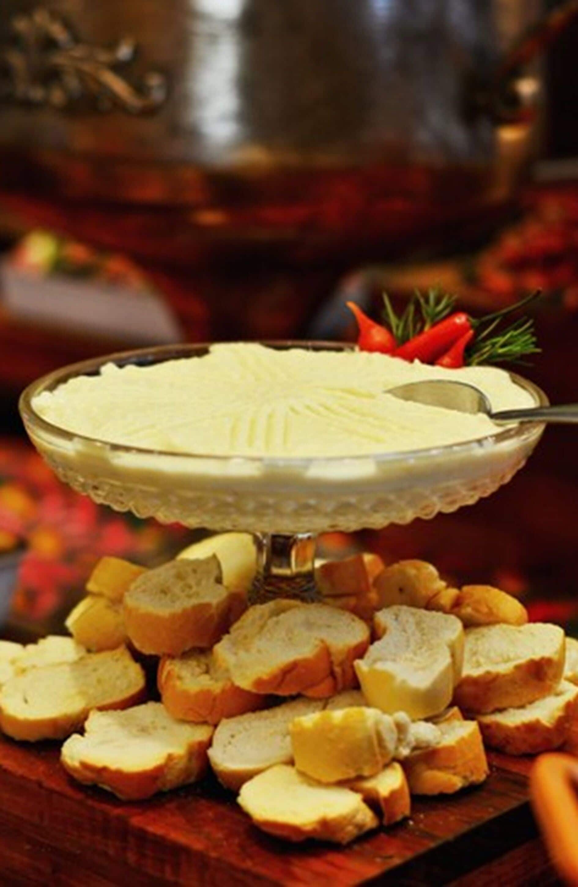 A glass pie dish with a creamy filling, surrounded by sliced bread on a wooden board.