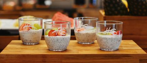 Cuatro vasos de pudín de chía con fruta sobre una mesa de madera.