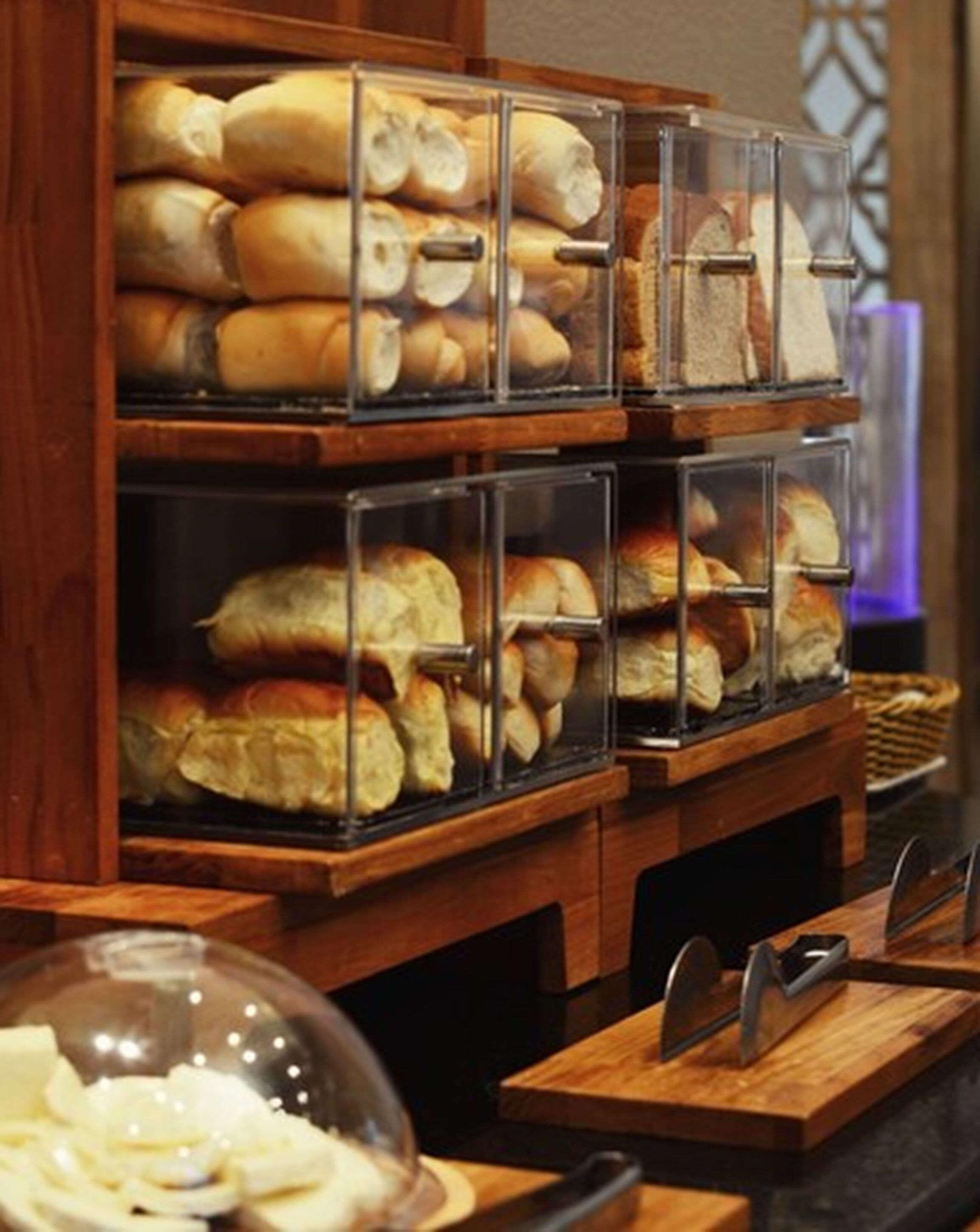 A bakery display with various breads and pastries in clear containers.
