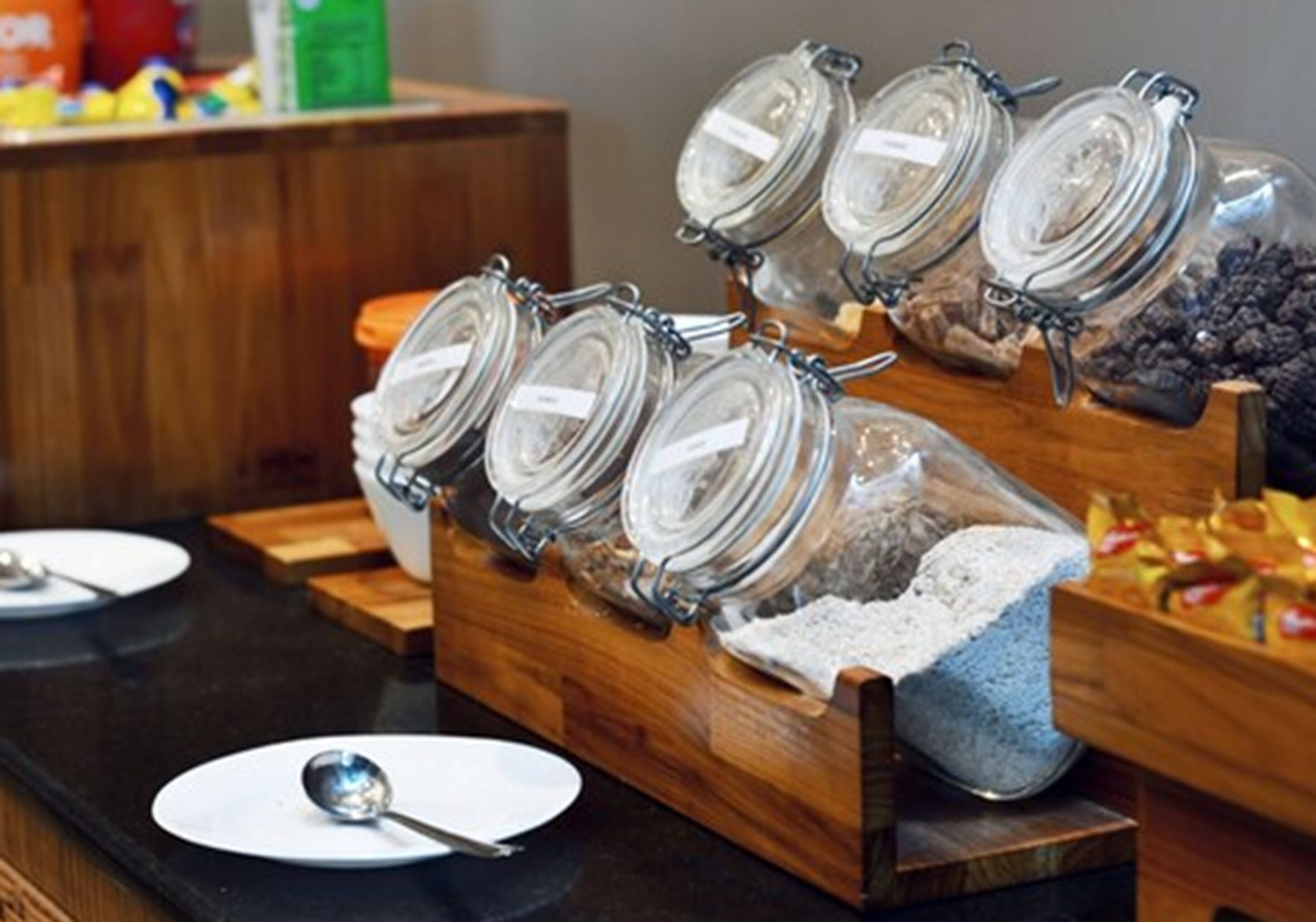 Un buffet composé de plusieurs bocaux en verre contenant différents aliments, d’un saladier rempli de farine et d’un plateau de collations.