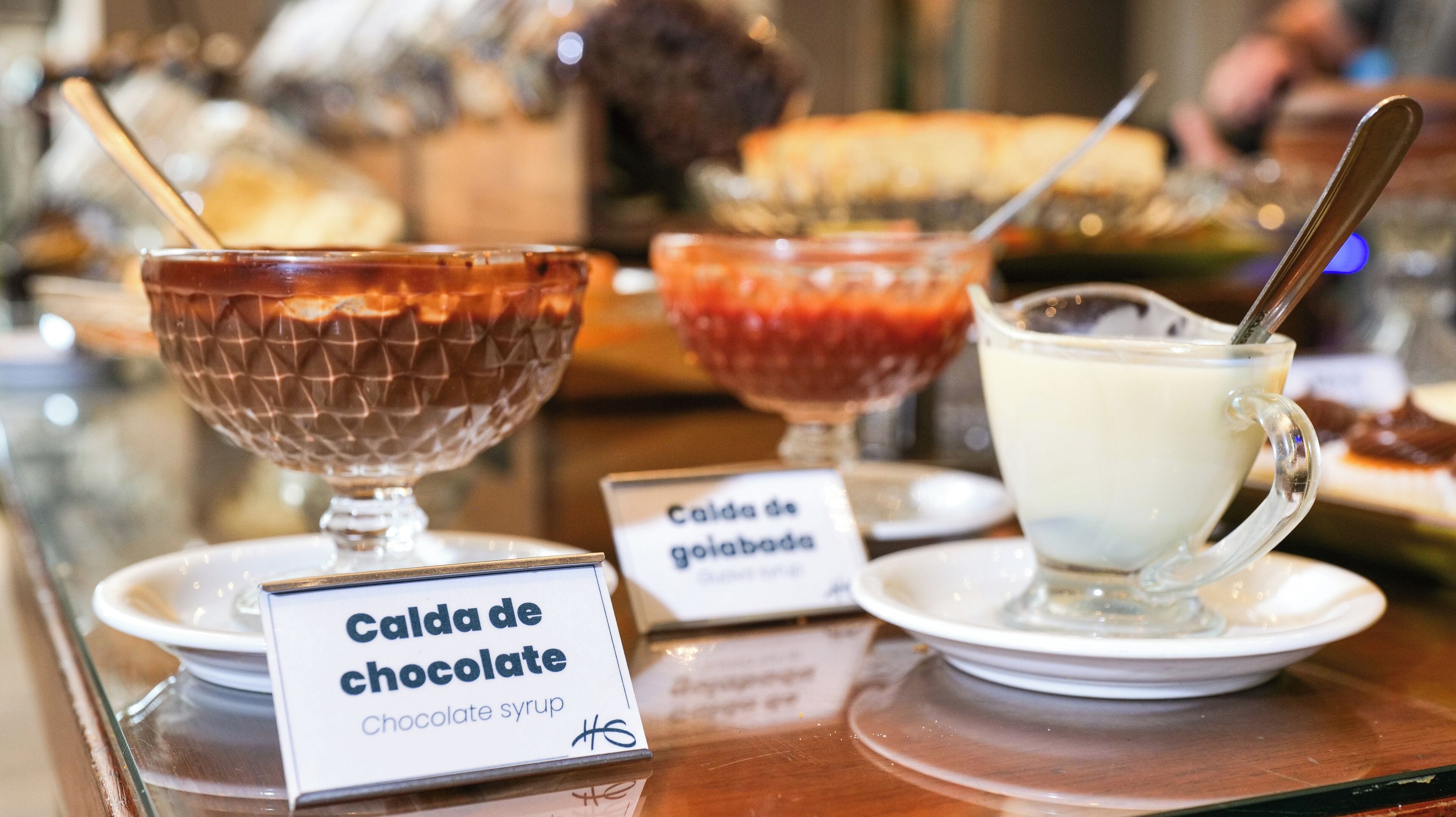Diverse desserts, waaronder chocoladesiroop, een glas melk en een rood dessert met een lepel.