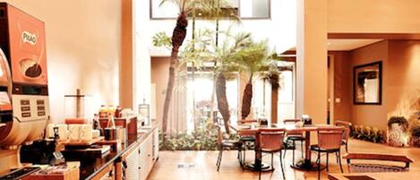 A restaurant with a long counter, a coffee machine, and several tables and chairs.