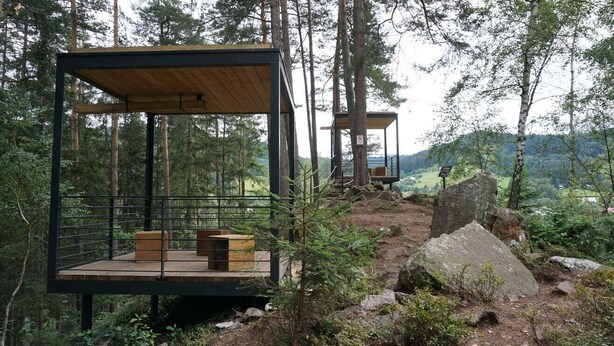 Two modern wooden cabins with metal railings, set in a forest with a view of a valley. - Penzion Staré časy (Horní Becva)