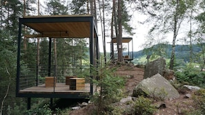 Two modern wooden cabins with metal railings, set in a forest with a view of a valley. - Penzion Staré časy (Horní Becva)