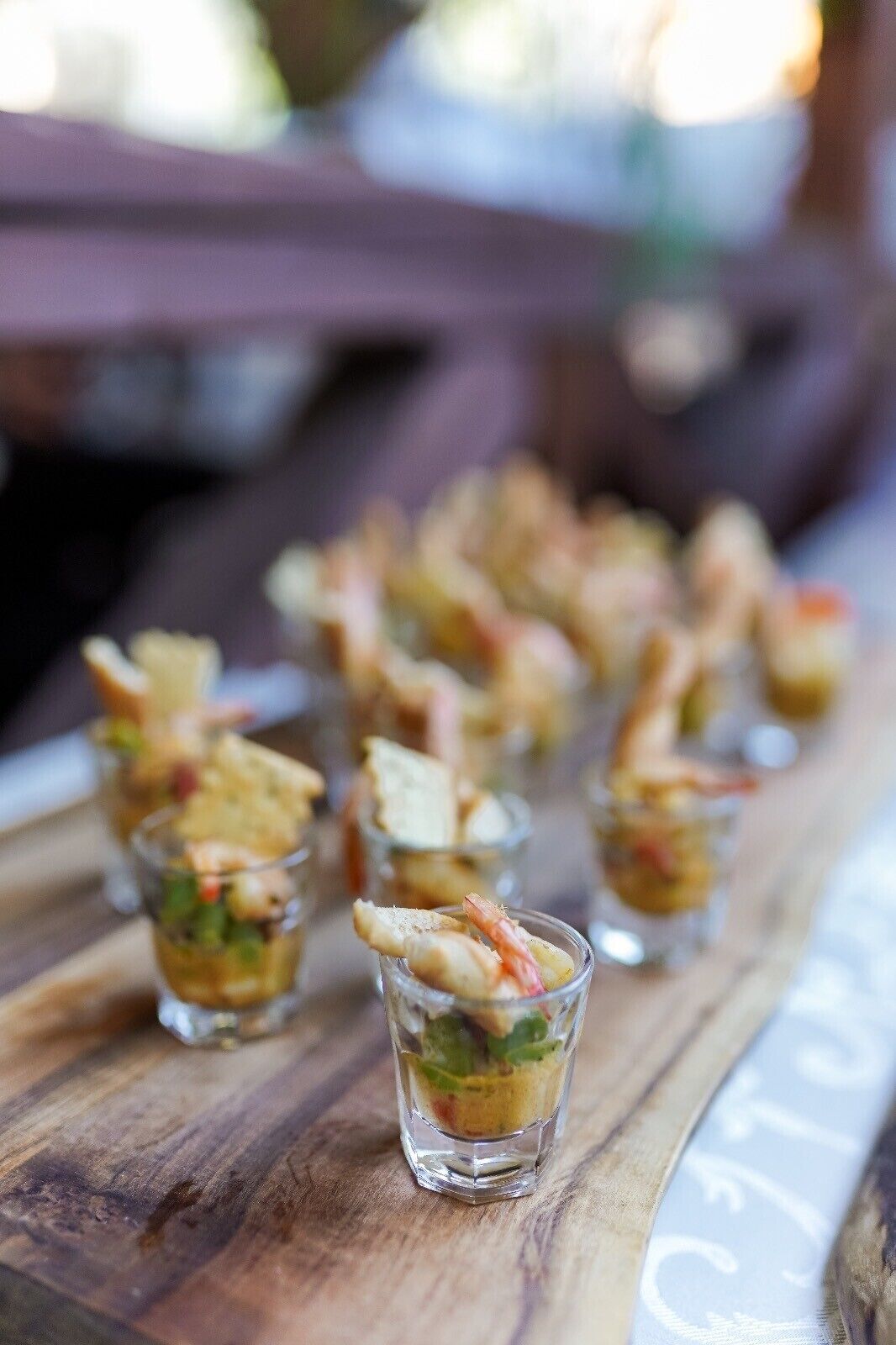 A wooden table with small glass cups containing appetizers.
