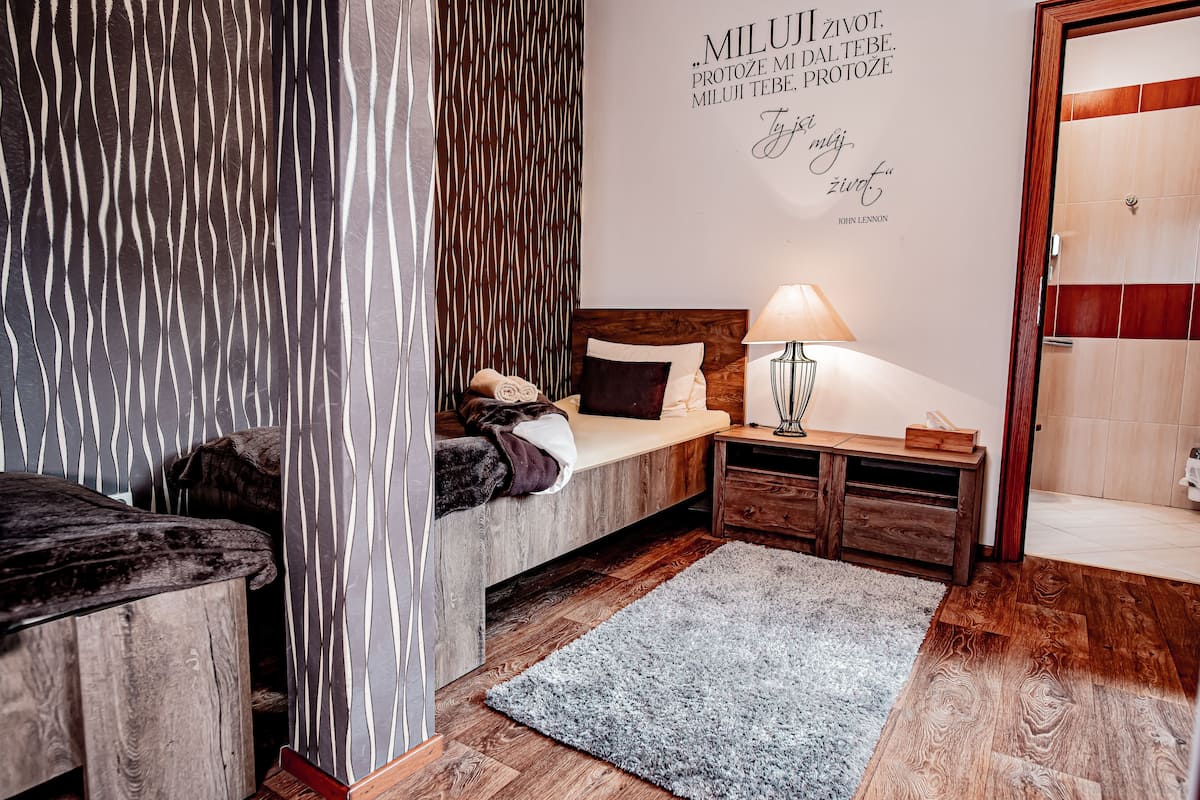Ein Schlafzimmer mit Bett, Nachttisch, Lampe und einem Zitat an der Wand.