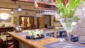 A restaurant interior with a wooden bar, tulips in a glass vase, candles, and a stone wall. - Penzion Staré časy (Horní Becva)