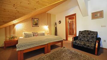 A bedroom with a wooden ceiling, a bed, a chair, and a nightstand.