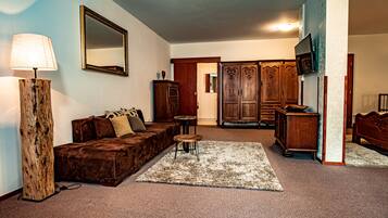A living room with a brown sofa, a wooden coffee table, a lamp, a mirror, and a TV on a stand.