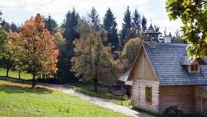 A rustic wooden cabin with a sloped roof, a small bell tower, and a wooden fence. - Penzion Staré časy (Horní Becva)