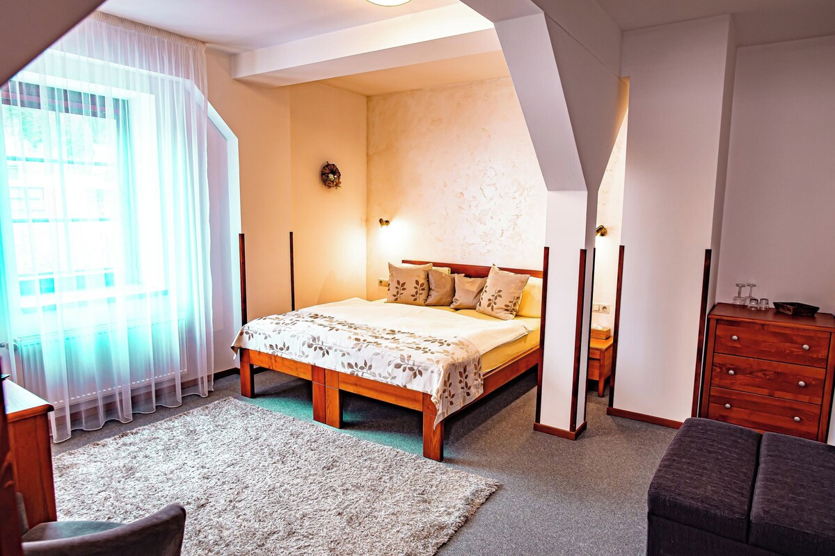 Une chambre à coucher avec un lit, une commode, une chaise et une fenêtre avec des rideaux.