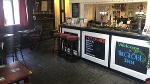 A bar area with stools, a menu board, and a welcome sign for The Globe Inn.