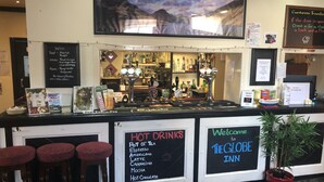 A bar area with a menu board listing hot drinks and a welcome sign for The Globe Inn.