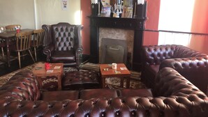 A cozy room with a fireplace, leather sofas, a wooden table, and a dining area with chairs.