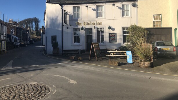 The Globe Inn, a white building with a traditional design, featuring a signboard and a small outdoor seating area.