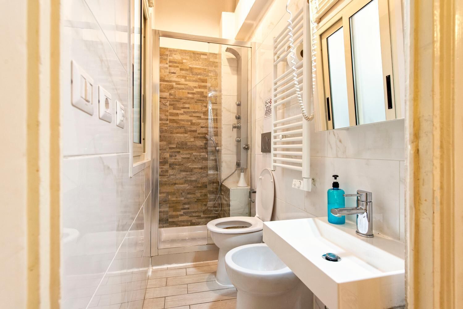 A modern bathroom with a shower, toilet, and sink.