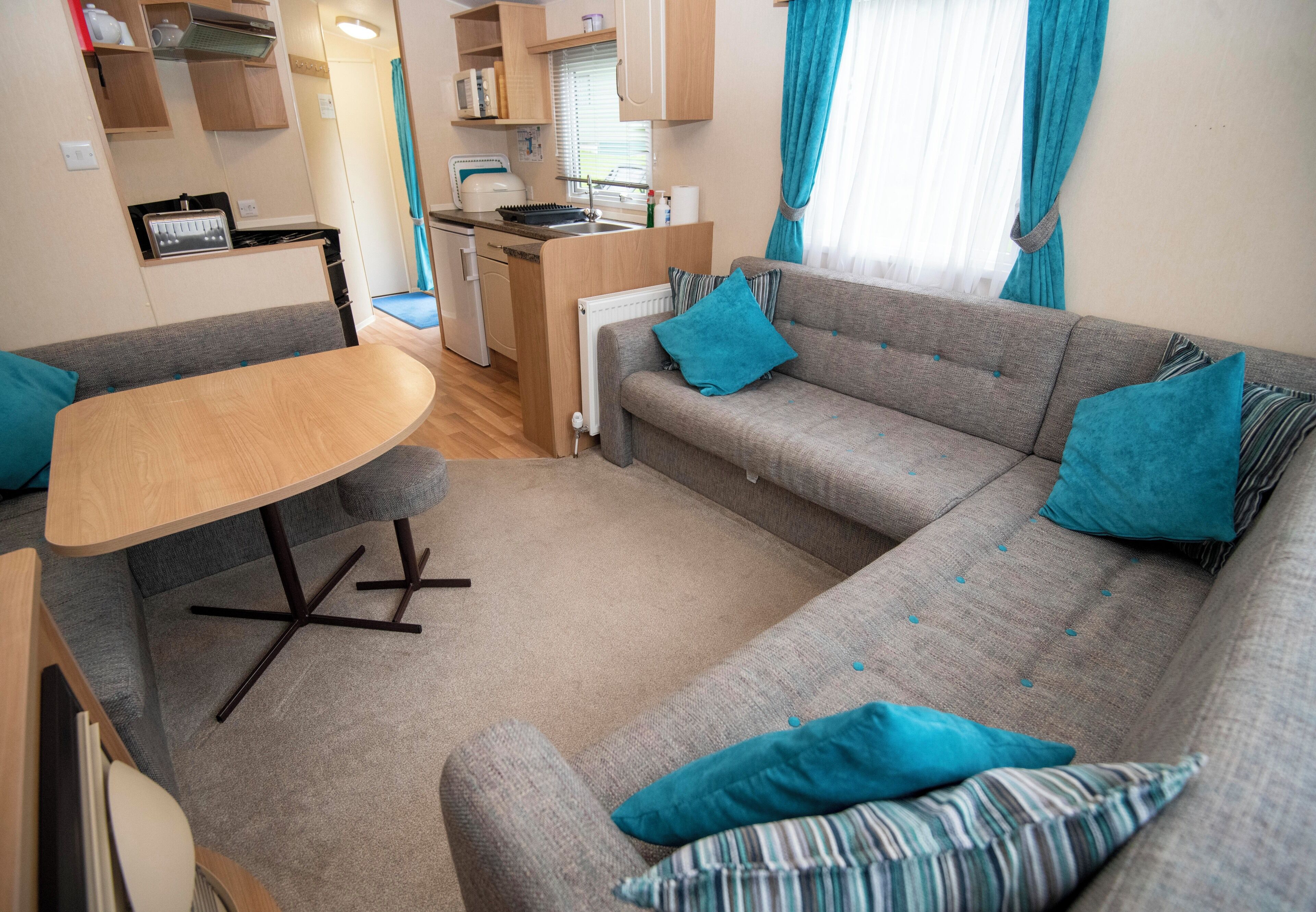 Ett kompakt bostadsutrymme med en soffa, ett litet matbord och ett litet kök.