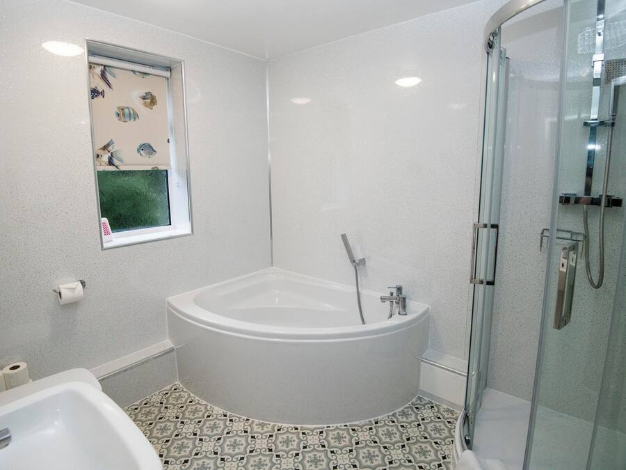 Un baño con bañera independiente, cabina de ducha de vidrio y baldosas de suelo estampadas.