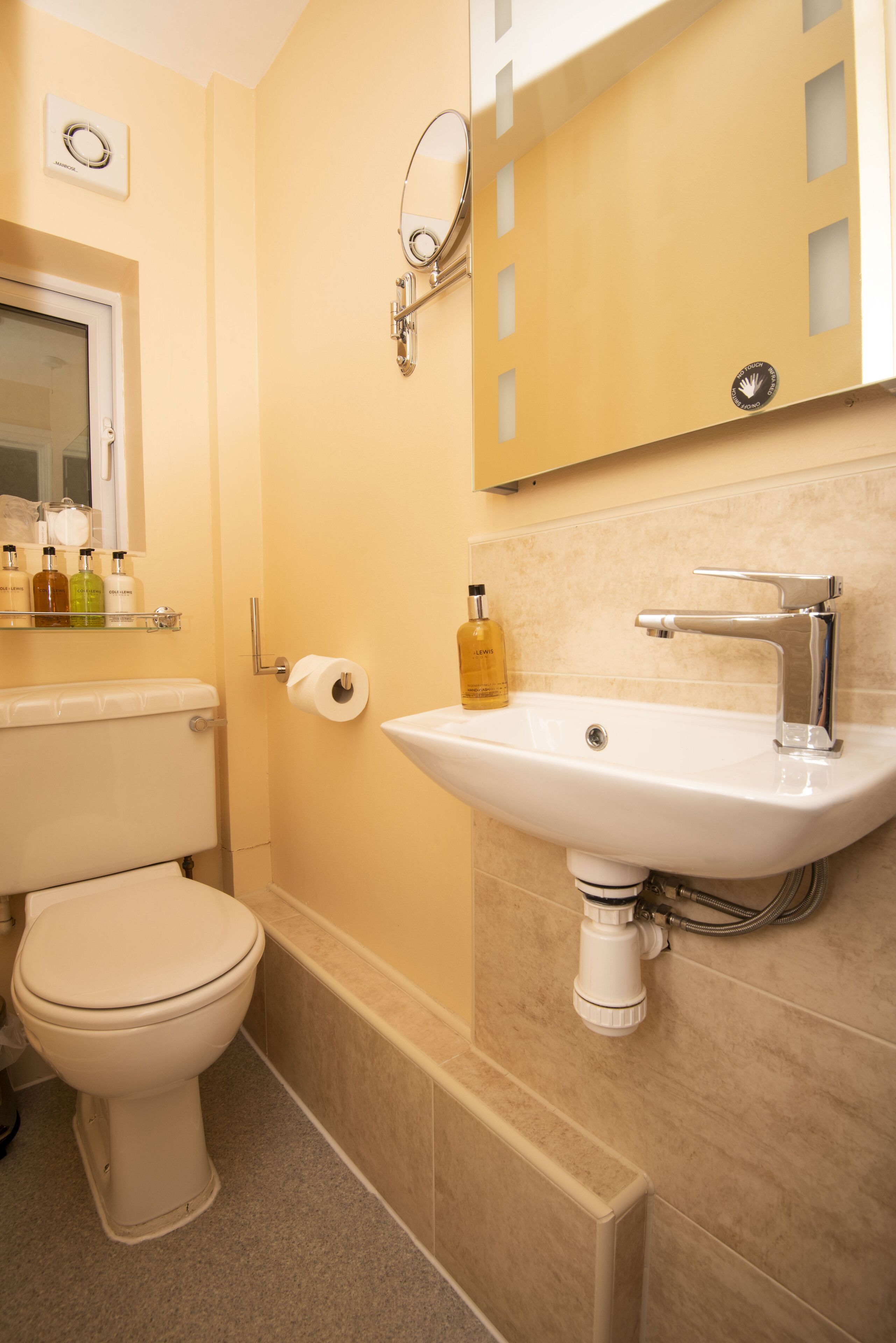 Un baño con inodoro, lavamanos y espejo.