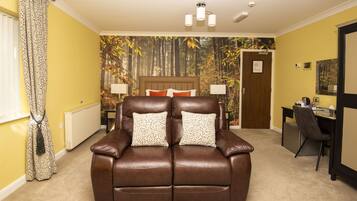 A room with a brown leather sofa, a desk, and a wall with a forest mural.