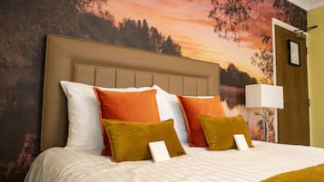 A neatly made bed with a headboard, multiple pillows, and a framed picture on the wall.