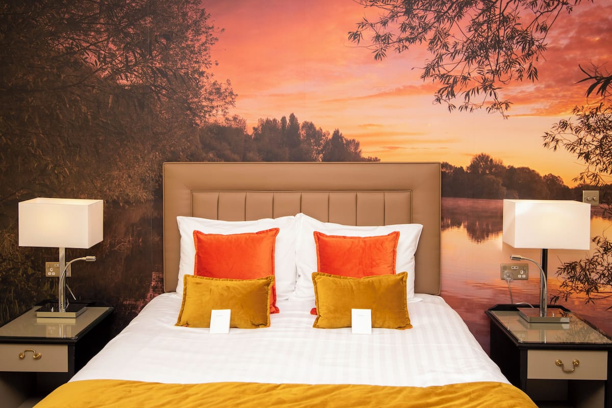 Een bed met hoofdeinde, twee nachtkastjes en kussens.