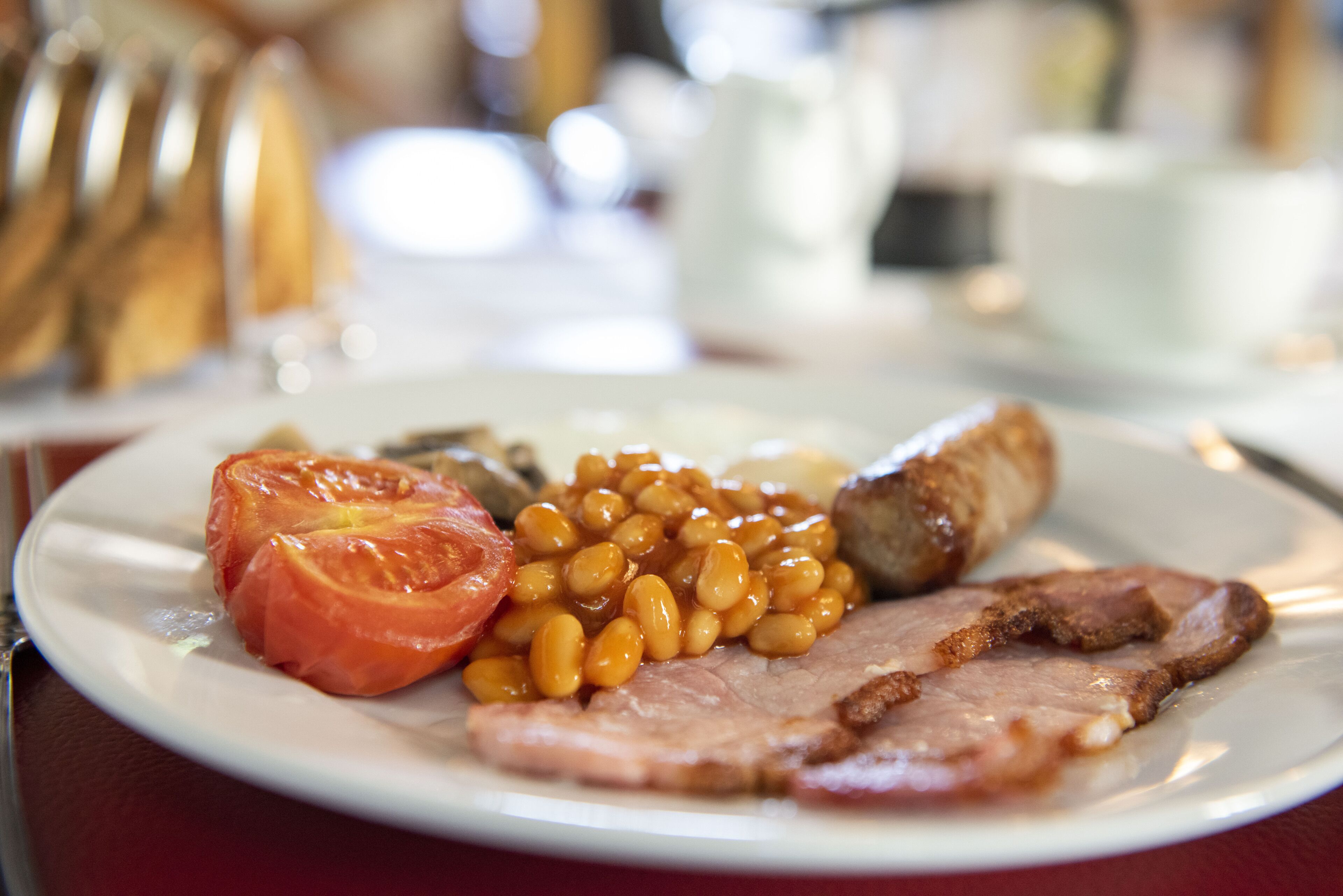 Un plato con alimentos, incluyendo frijoles, tocino y tomate.