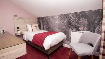 A bedroom with a bed, a chair, a desk, and a wall with a nature-themed mural.