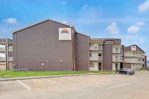 A brick building with a sign for an extended stay hotel, a parking lot, and a car parked in front.